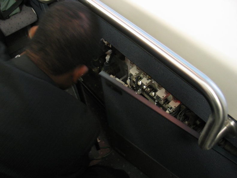 JFK AirTrain agent plays with some electrical stuff in a cabinet beneath the closed manual operation control stand. Something wa