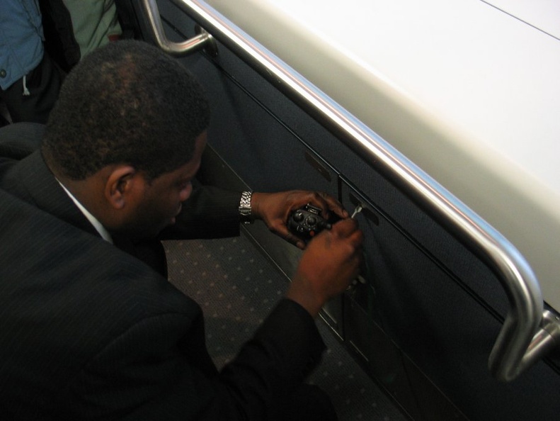 JFK AirTrain agent plays with some electrical stuff in a cabinet beneath the closed manual operation control stand. Something wa